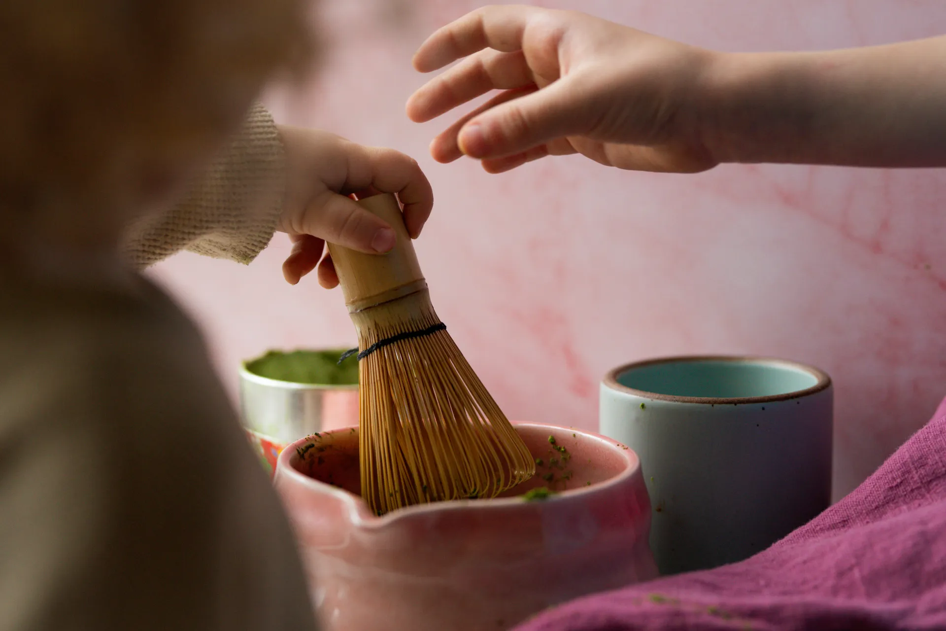 Children's hands sharing in the matcha ritual