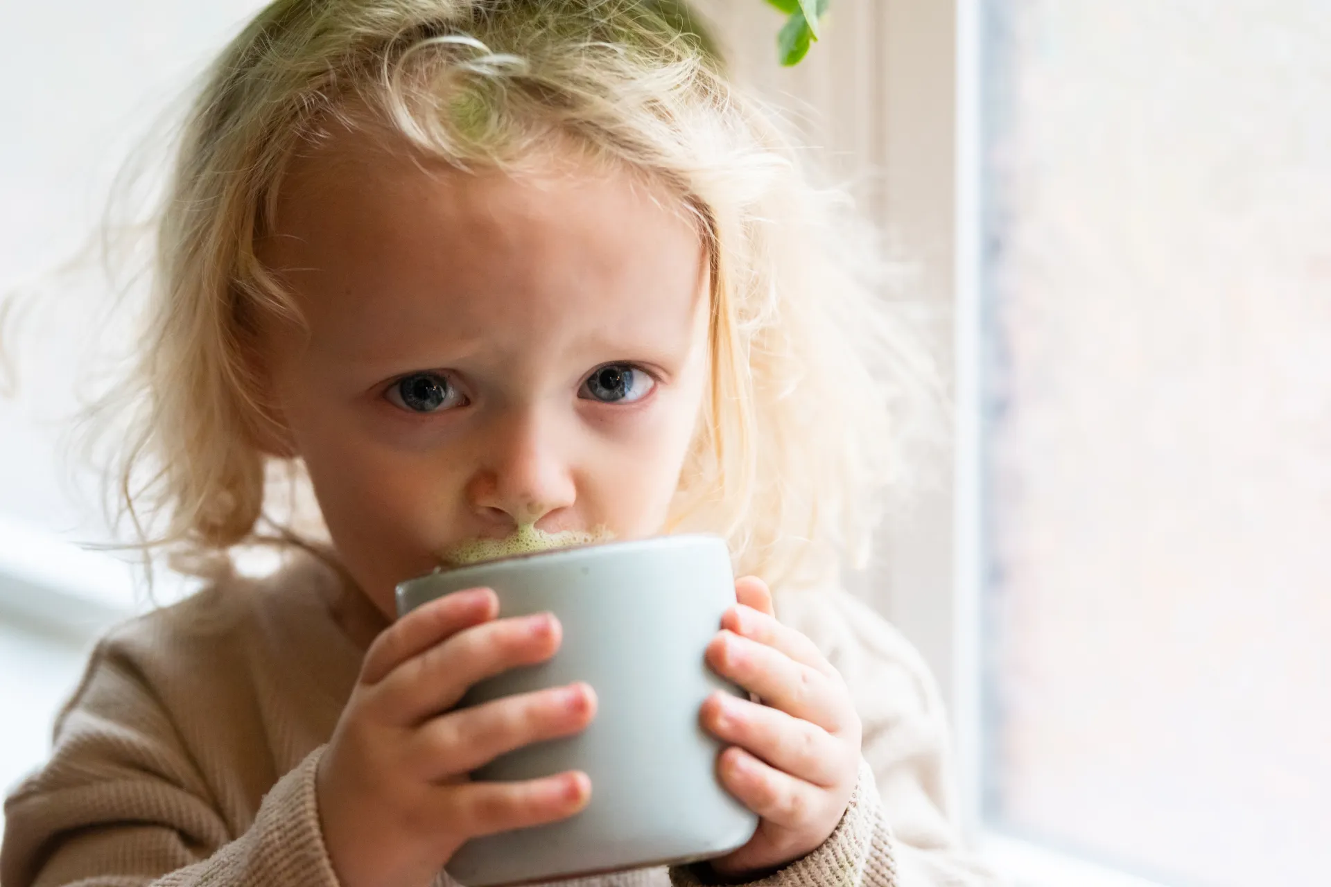 A young child sipping a matcha latte